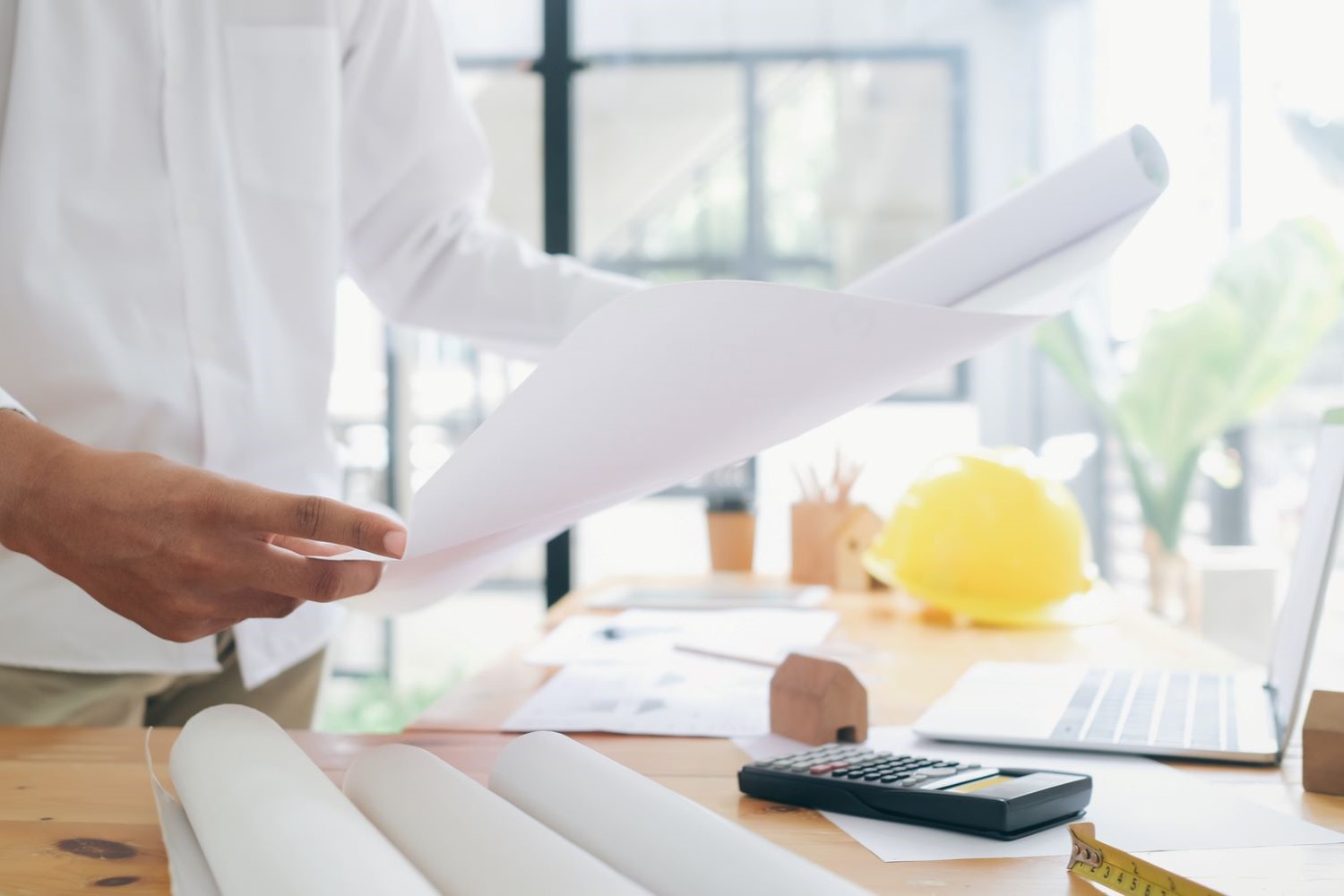 Construction professional reviews project plans with a calculator during early project cost planning.