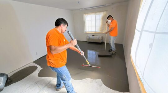 Level 3 Construction crew members apply self-leveling floor compound inside a Best Western Escondido guest room during ongoing renovation work.