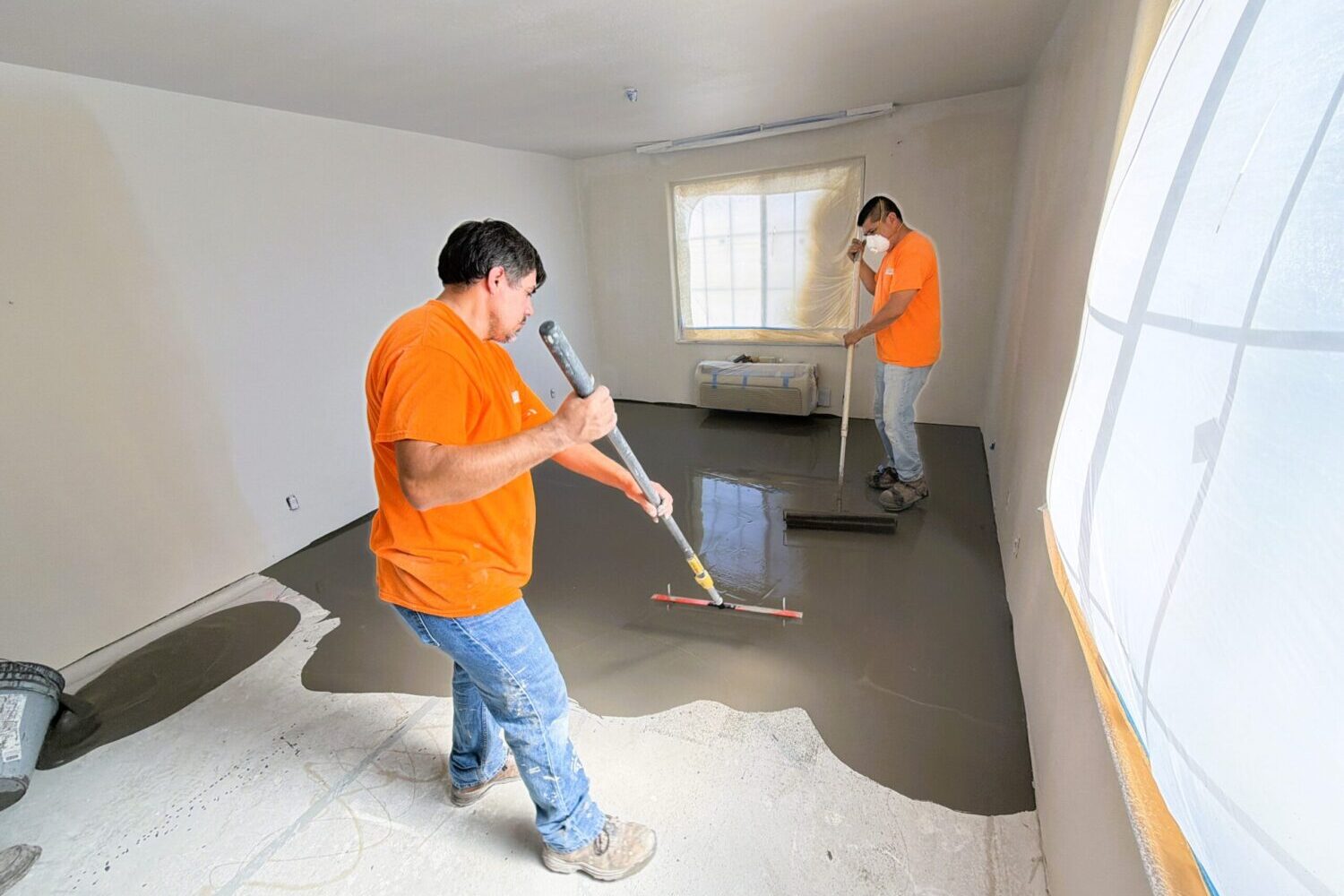 Level 3 Construction crew members apply self-leveling floor compound inside a Best Western Escondido guest room during ongoing renovation work.