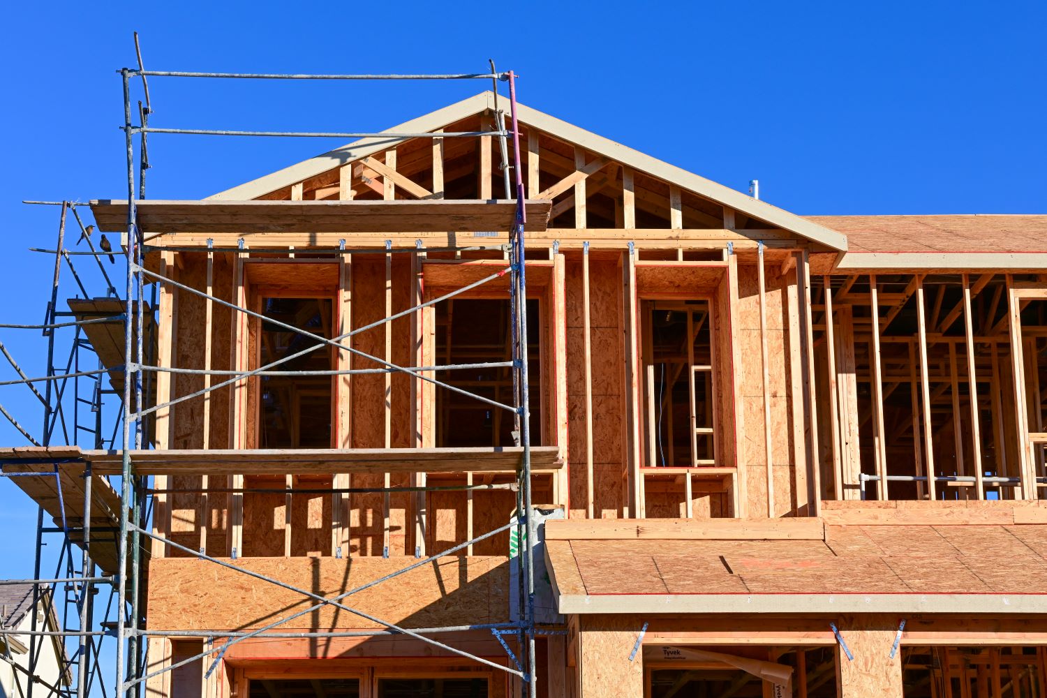 Upper portion of a multistory workforce housing building under construction, with wood framing and scaffolding visible.