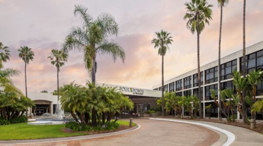 Exterior view of the Four Points San Diego hotel in Kearny Mesa, featuring palm trees, landscaped grounds, a fountain, and the main entrance. The property is slated for rebranding and conversion to a Marriott Tribute Portfolio hotel, with Level 3 Construction serving as general contractor.