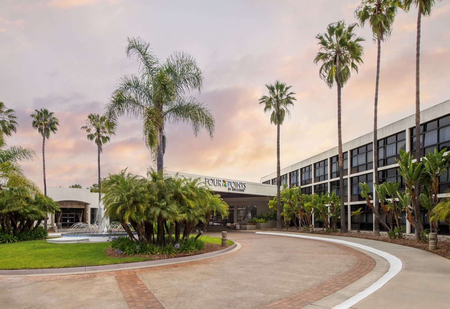 Exterior view of the Four Points San Diego hotel in Kearny Mesa, featuring palm trees, landscaped grounds, a fountain, and the main entrance. The property is slated for rebranding and conversion to a Marriott Tribute Portfolio hotel, with Level 3 Construction serving as general contractor.