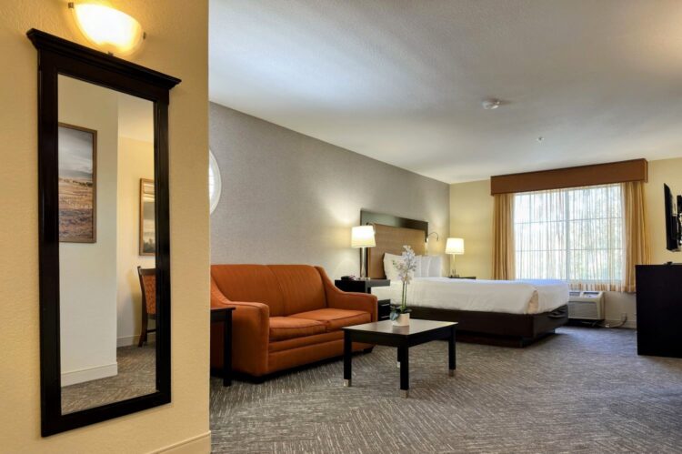 Renovated king guest room at the Best Western Escondido Hotel featuring a king bed, loveseat, coffee table, and updated finishes.