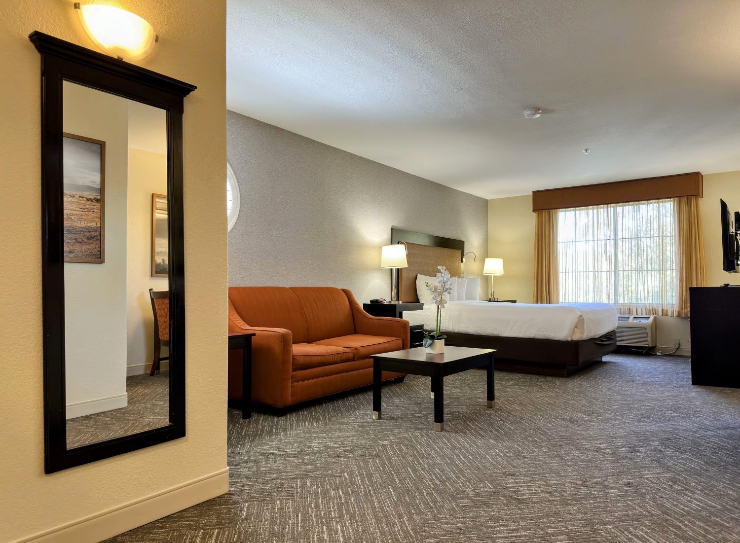 Renovated king guest room at the Best Western Escondido Hotel featuring a king bed, loveseat, coffee table, and updated finishes.