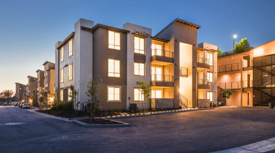 La Costa Family Apartments exterior at dusk in Carlsbad, showing contemporary architecture, varied massing, and illuminated balconies