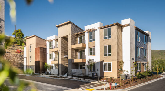 Exterior view of La Costa Family Apartments with stucco façade, private balconies, and coastal-inspired design in Carlsbad, California.