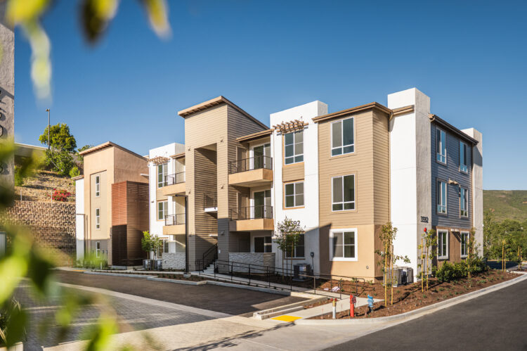 Exterior view of La Costa Family Apartments with stucco façade, private balconies, and coastal-inspired design in Carlsbad, California.