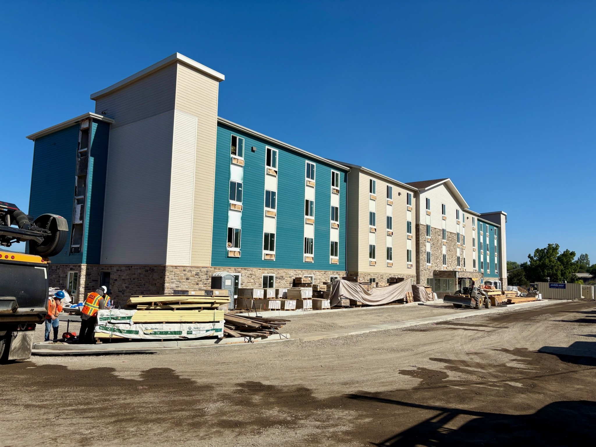 Exterior view of the WoodSpring Suites Santee hotel, showing a modern multi-story building with neutral-colored siding, large windows, and a well-maintained entrance area